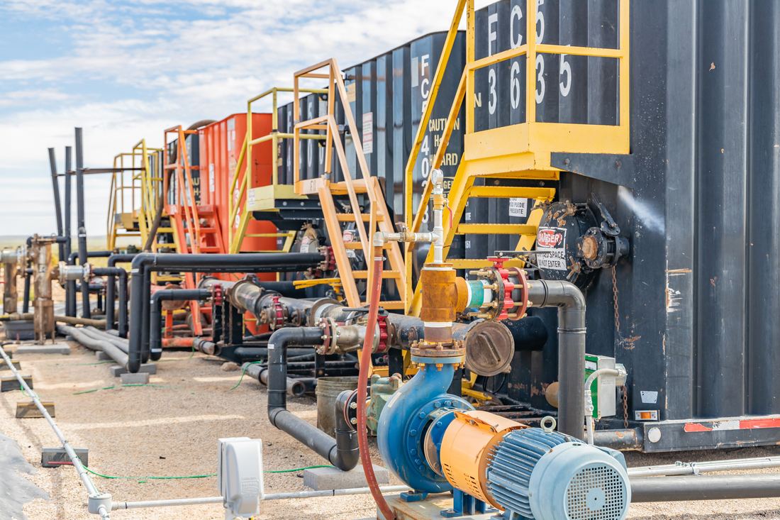 Blue transfer pump on a skid beside the tank battery